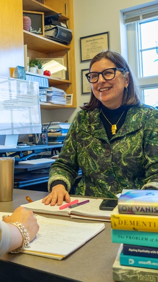 Dr. Janet Durkee-Lloyd smiling at a student in her office.