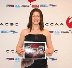 Connors stands in front of a CCAA backdrop holding the CCAA Player of the Year award