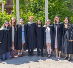 A group of Bachelor of Education graduates stand in their grad gowns in front of McCain Hall on ������������ campus.
