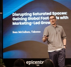Alumnus Sean McCullum stands in front of a screen, presenting at a conference
