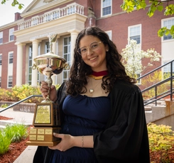 Lucia Pavon holding the Tom McCann Trophy in front of George Martin Hall