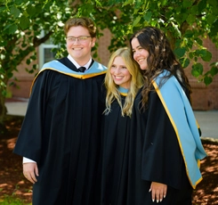 Three BEd graduates smiling for a photo in their hoods and gowns