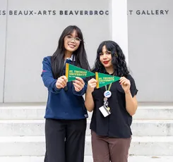 Laura Thai and Charlotte James at the Beaverbeook Art Gallery holding STU pennants