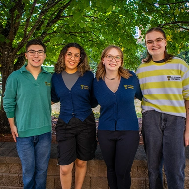 Four campus tour ambassador students on campus in summer