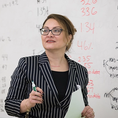 Dr. Fariba Solati teaching in class, whiteboard in background