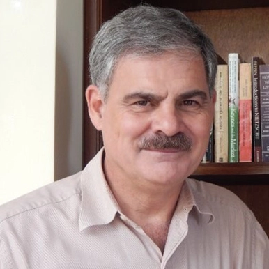 Headshot of Dr. Juan Alberto Fuentes Knight next to a bookshelf