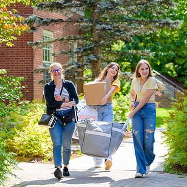 Three women moving boxes into residence