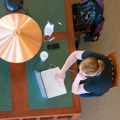 Top down view of student using laptop in study hall