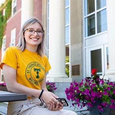 Student sitting outdoors at a picnic table next to flowers