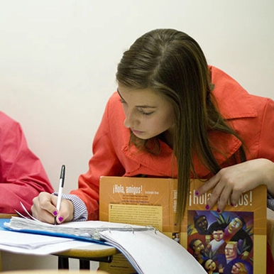 A student holding a textbook and taking notes