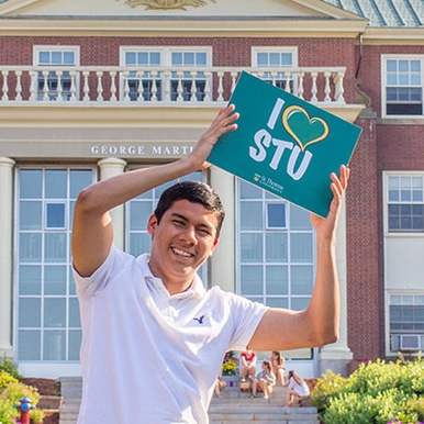 A student smiling and holding a STU sign