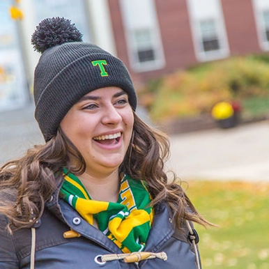 A student wearing a STU beanie and laughing