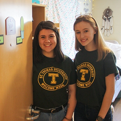 Two students standing in a doorway in residence, smiling