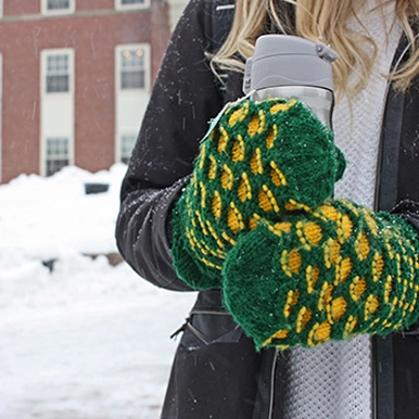 Student wearing mittens holding a coffee in the winter
