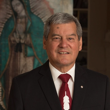 Hon Graydon Nicholas in front of a painting of the Virgin Mary