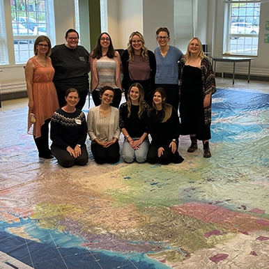 students standing on large Indigenous floor map