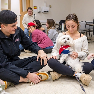 Students visiting with a therapy dog
