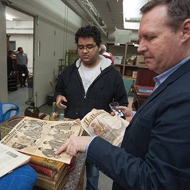 A photo of a history professor and student looking at archives