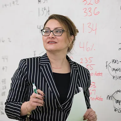 Dr. Fariba Solati teaching in class, whiteboard in background