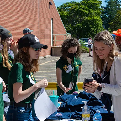 4 Students gathered at table outdoors and helping with move-in