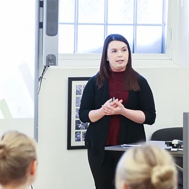 A student standing in front of a projector presenting