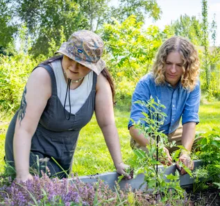 A female student and a male professor work together in a garden.