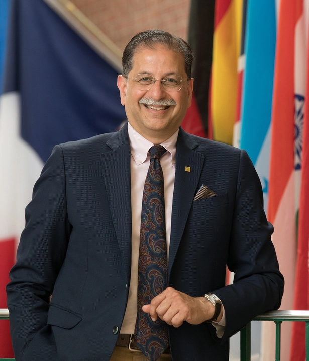Dr. Farooqi standing on campus in front of flags