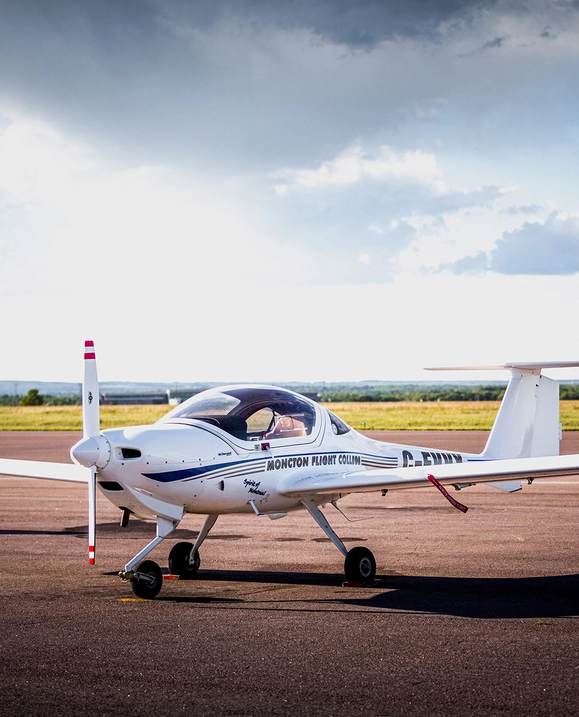A small white plane outside on the tarmac on a cloudy day