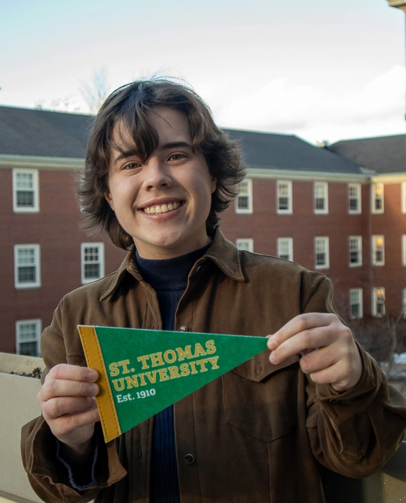 A student proudly holds out a STU pennant on campus