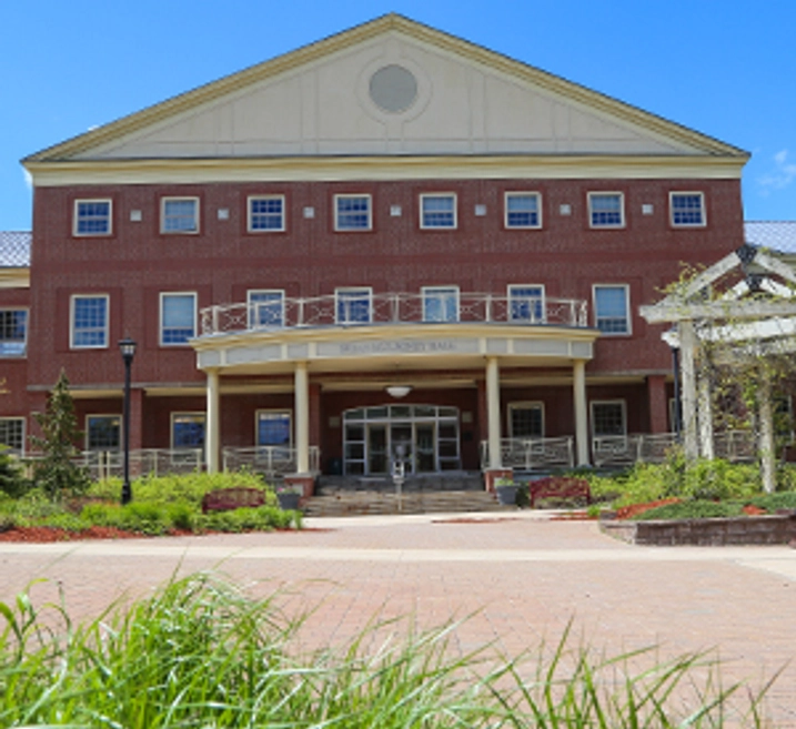 A close up of the name on Brian Mulroney Hall, shot through golden fall leaves.