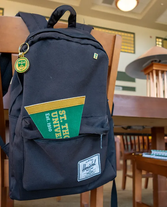 A black backpack hangs over a chair in the study hall. A STU pennant pokes out of the front pocket.