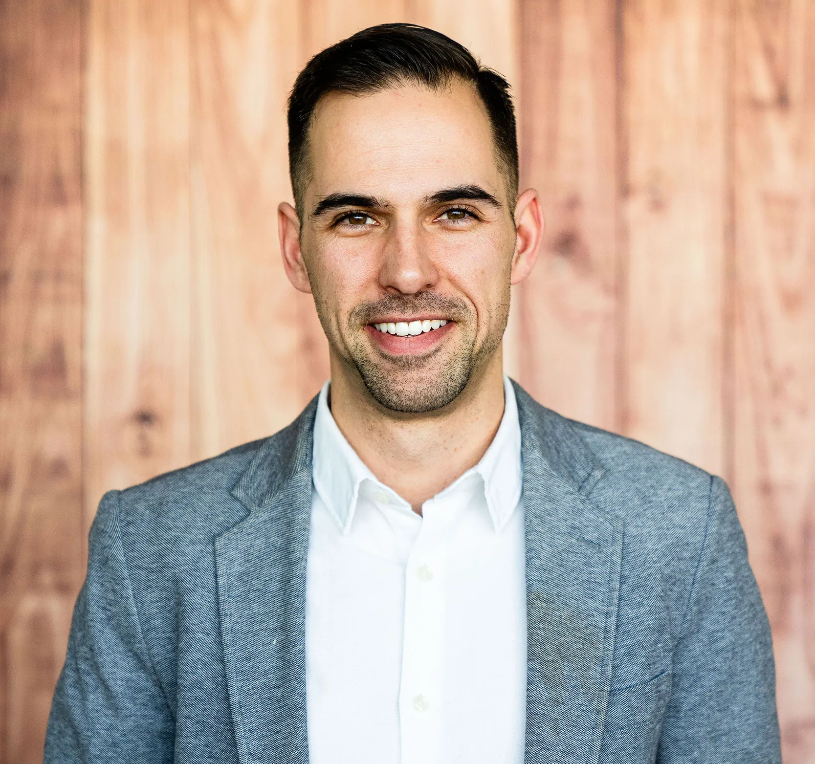 A photo of 鶹ҳ alumnus Jason Cassidy standing in front of a wood panelled wall