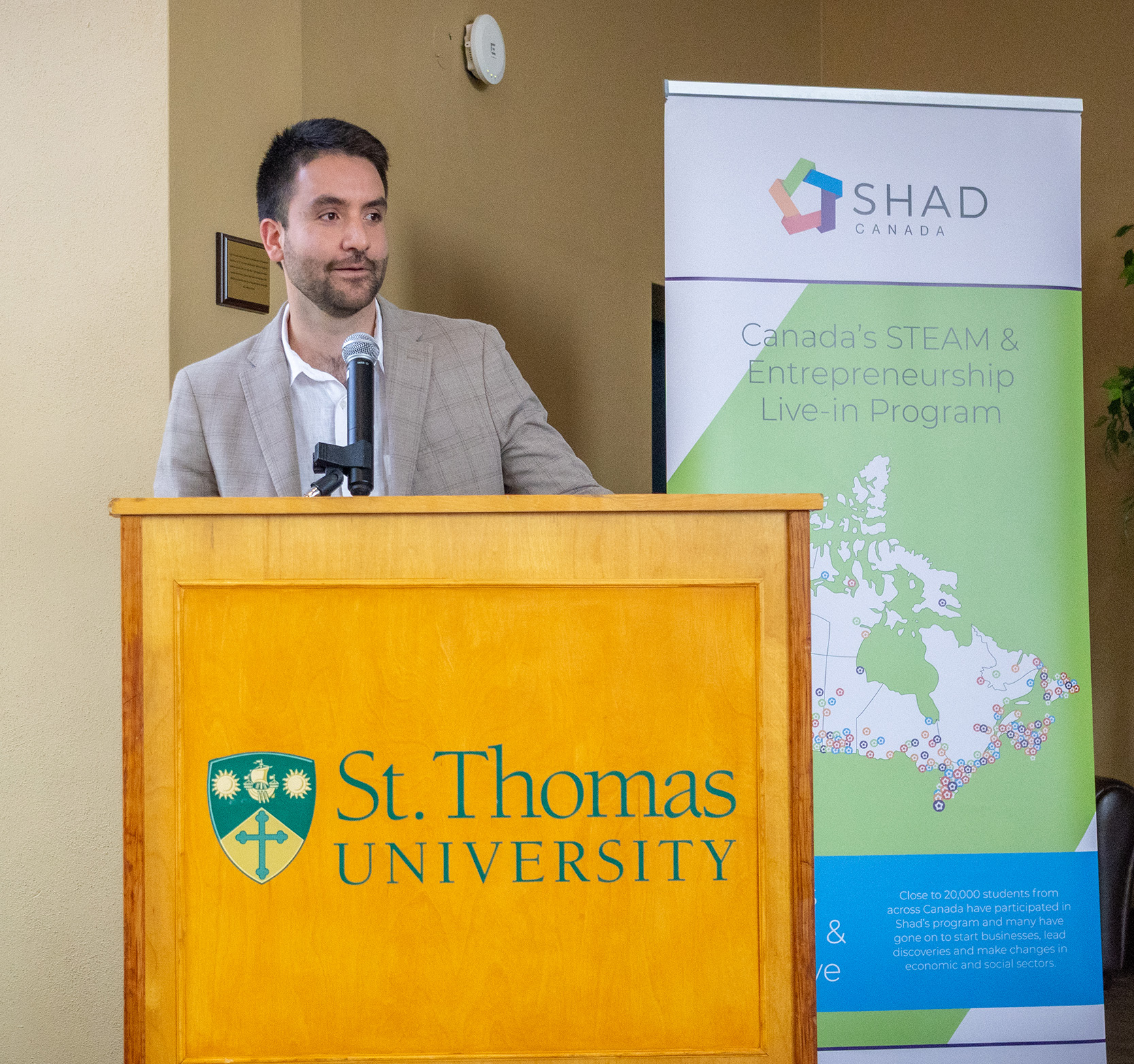 Jimy Beltran stands behind a podium with the words 