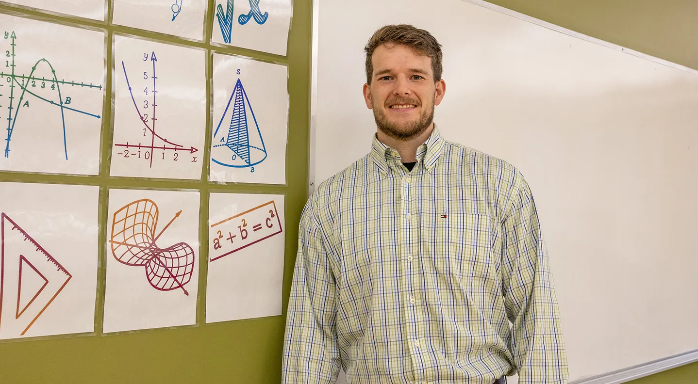 A male Bachelor of Education student stands in a dress shirt at the front of the classroom