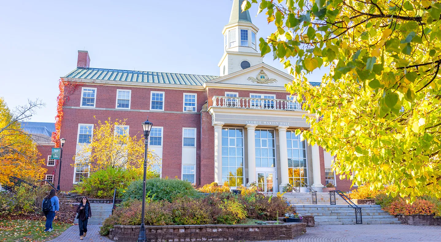 A photo of George Martin Hall in the fall with changing leaves in the foreground.