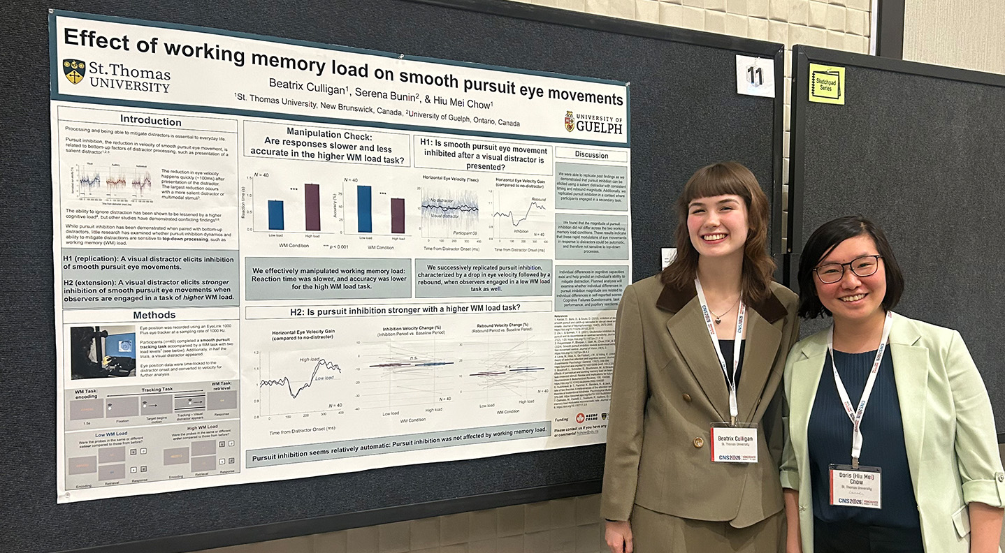 A female student and professor stand in front of a poster displaying their research