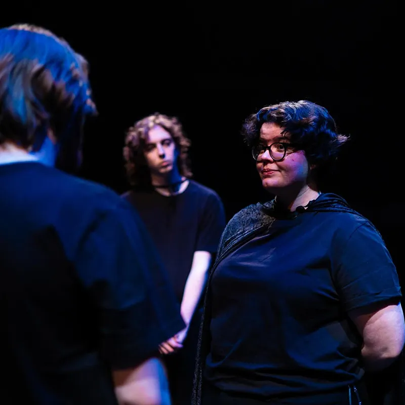 Three individuals stand in the Black Box Theatre during a production of Macbeth