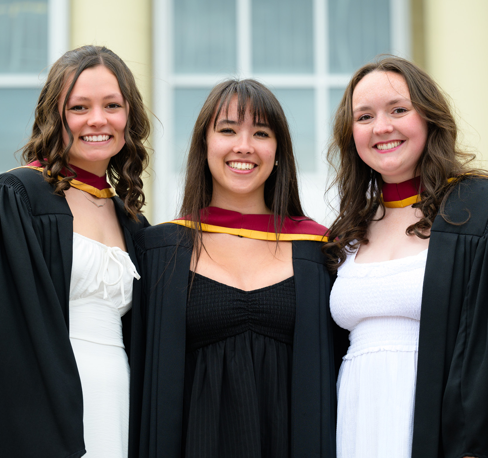 three grads standing outside GMH after convocation