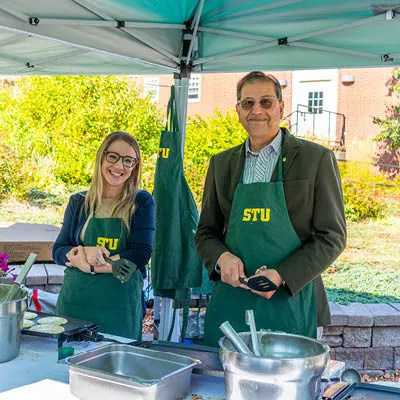 a staff member and the president serving Breakfast to students