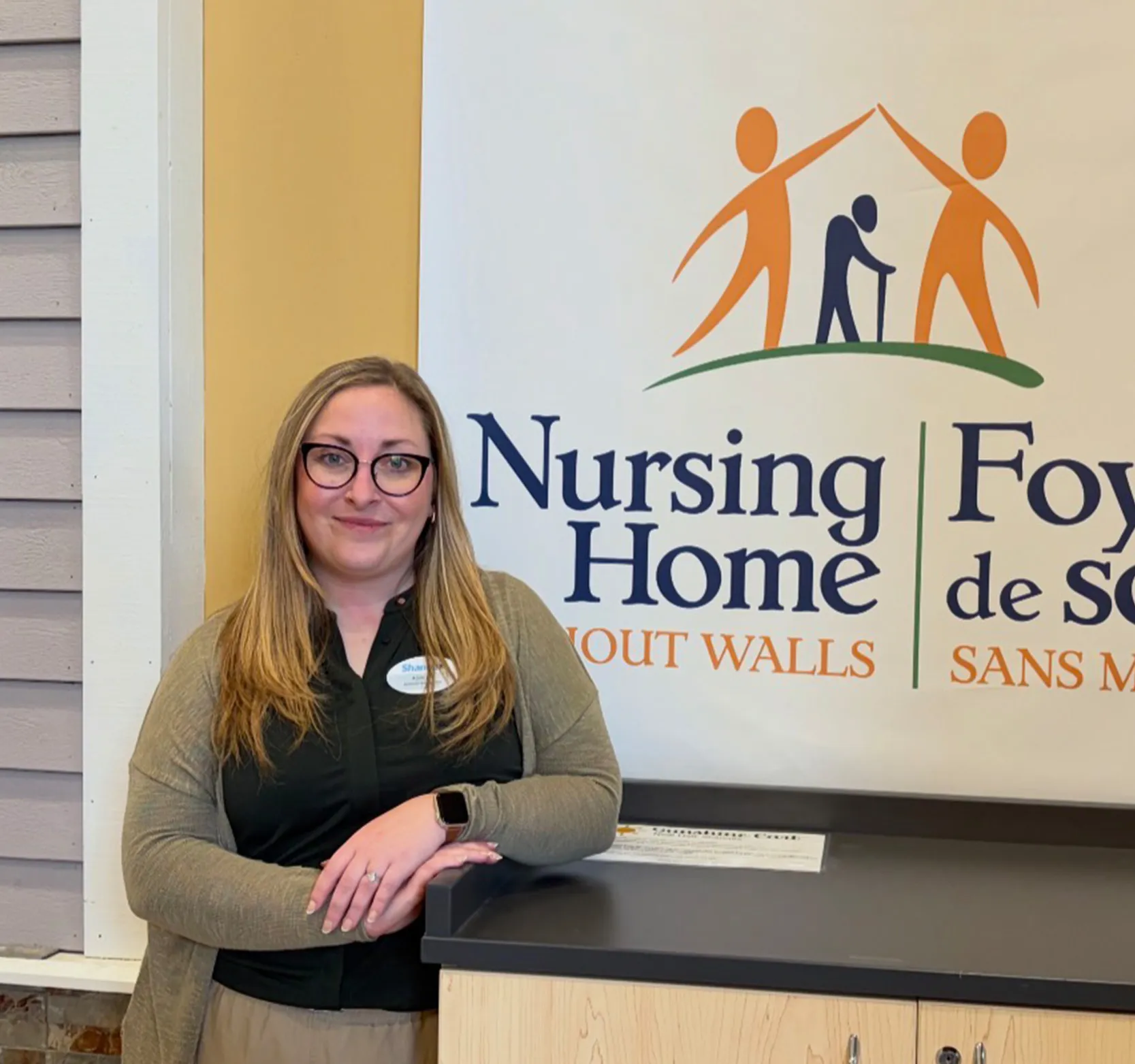 Ashley standing in front of Nursing Home Without Walls logo