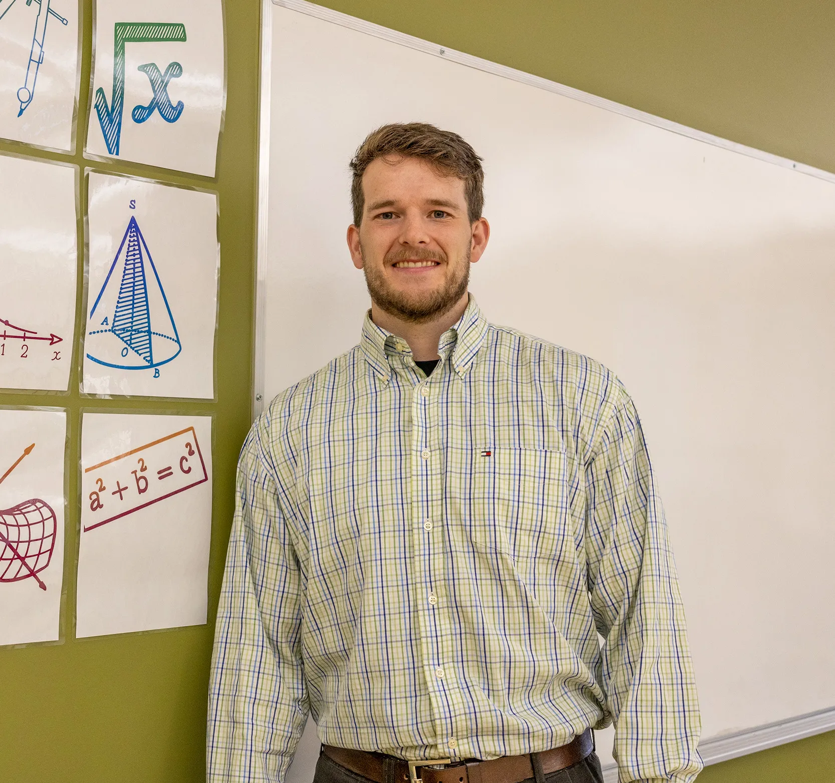 Brent Standing in classroom next to white board math posters