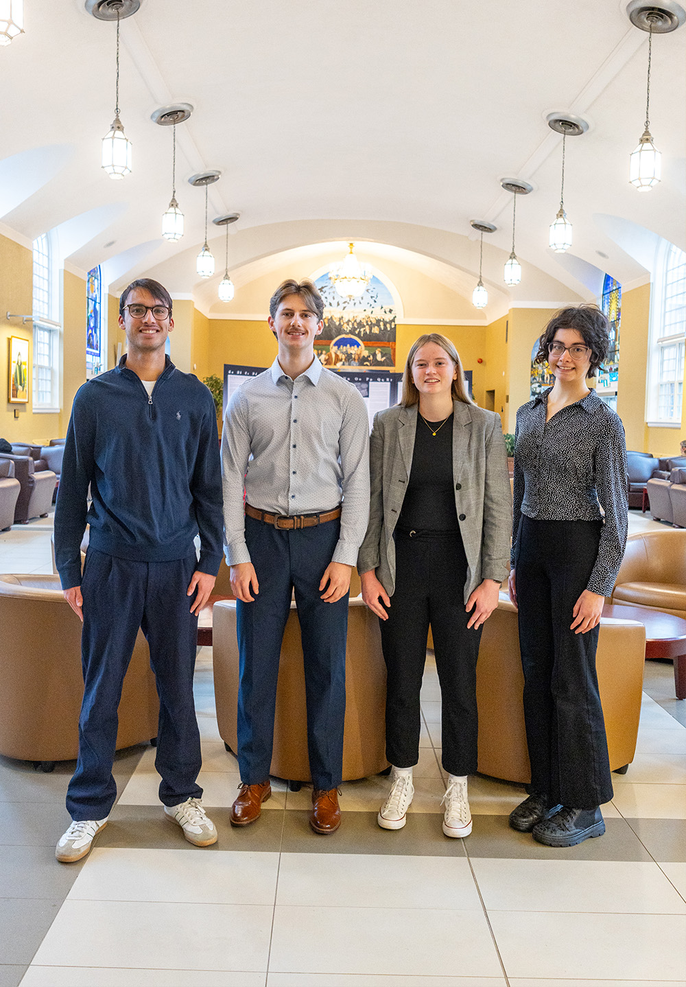 Two male and two female students stand together in the Great Hall