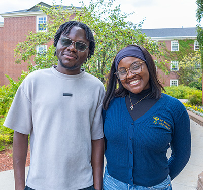 Picture of two scholarship students on campus smiling in early fall