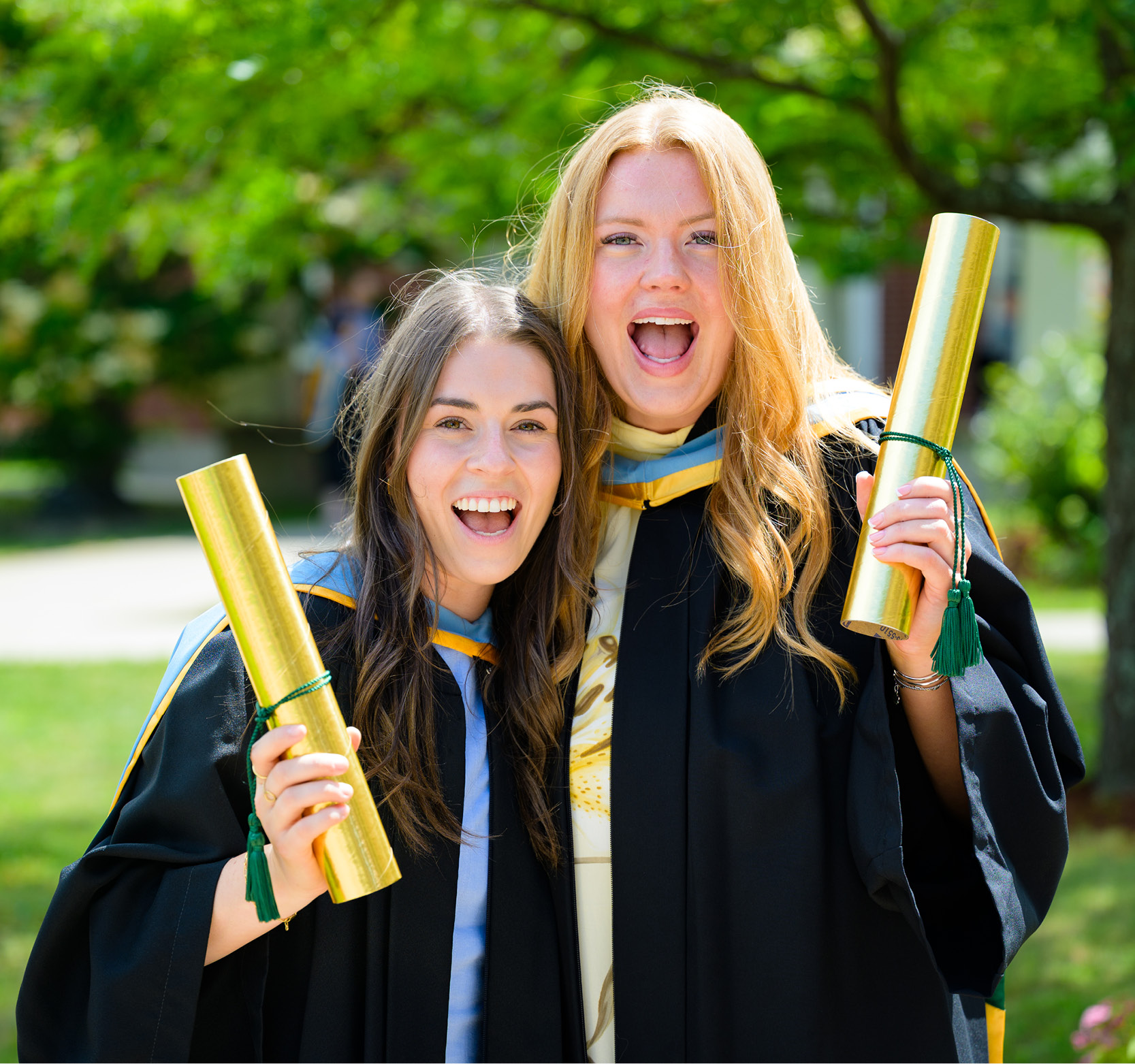 Two happy grads holding diplomas