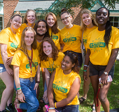 A group of student wearing gold 91ŷ����Ʒ t-shirts standing outside smiling